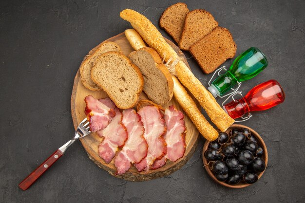 Top view fresh sliced ham with bread slices on dark background