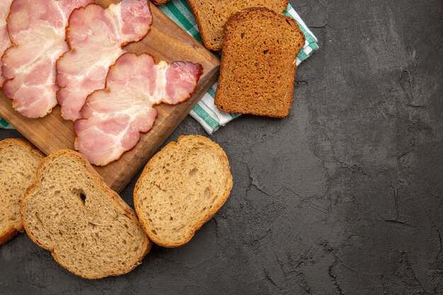 Top view fresh sliced ham with seasonings and bread on dark background