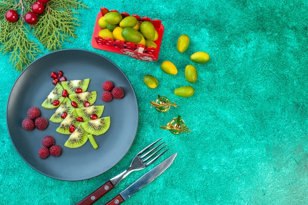 Top view fresh sliced kiwis with raspberries on green background