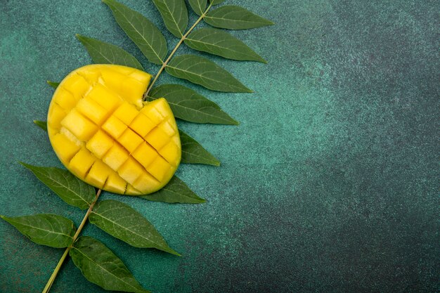 Top view of fresh sliced mango with leaf on green