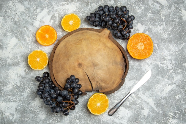 Top view fresh sliced oranges with black grapes on white surface citrus juice ripe fresh fruit