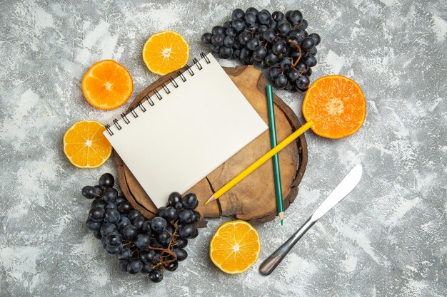 Top view fresh sliced oranges with black grapes on white surface fresh citrus juice ripe fruit