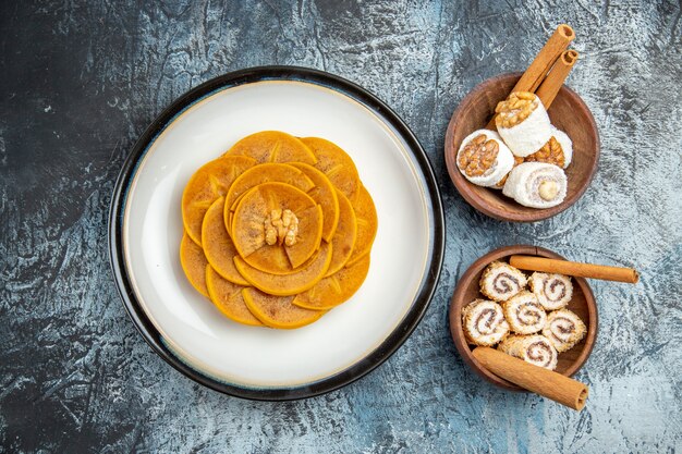 Top view of fresh sliced persimmons with confitures on dark surface