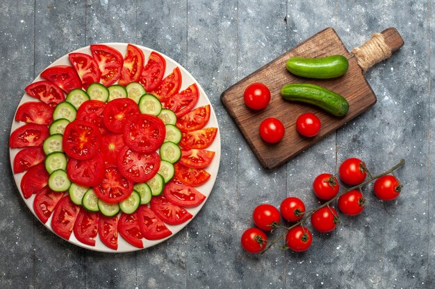 회색 소박한 공간에 오이로 우아하게 디자인 된 상위 뷰 신선한 슬라이스 토마토