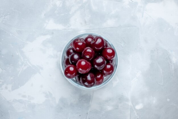 Top view of fresh sour cherries inside glass cup on light-white desk, fruit sour berry vitamine photo