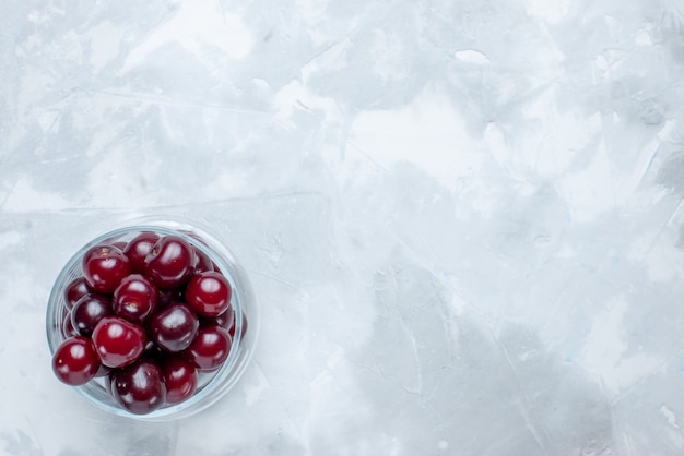 Top view of fresh sour cherries inside little glass cup on light-white desk, fruit sour berry vitamine