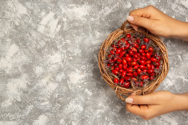 Бесплатное фото Вид сверху свежие кислые кизилы внутри корзины на белом столе фруктовые ягоды витамин кислые спелые растения дерево