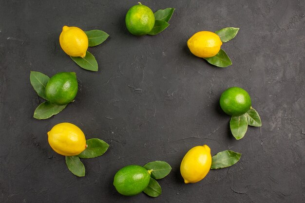 Top view fresh sour lemons on dark-grey floor lime fruit citrus