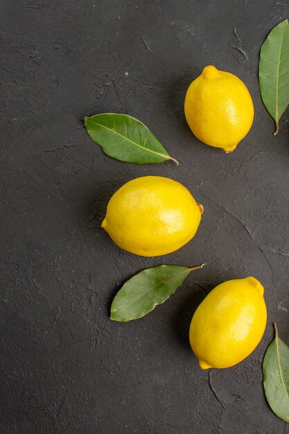 Вид сверху свежие кислые лимоны, выложенные на темном полу, фрукты, цитрусовые, желтый, лайм