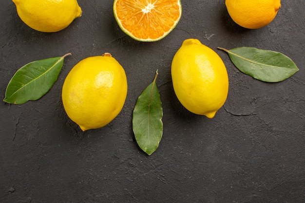 Vista dall'alto limoni freschi e aspri allineati sul tavolo scuro, agrumi giallo lime