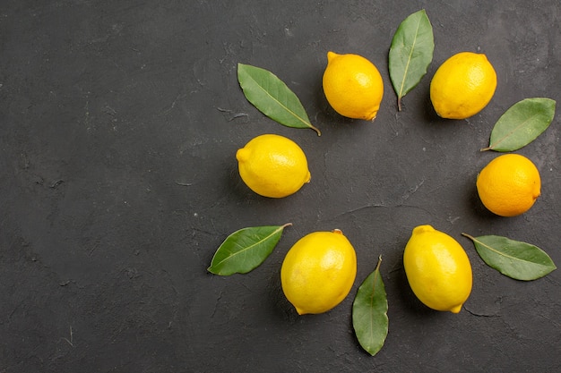 Vista dall'alto limoni freschi e aspri allineati sul tavolo scuro, frutta agrumi giallo lime