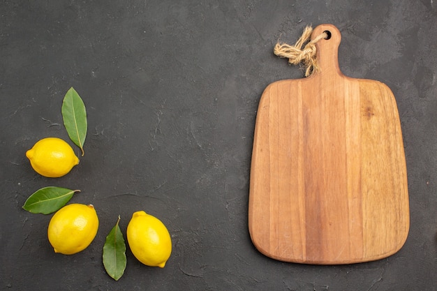 Top view fresh sour lemons with leaves on dark table fruit lime yellow citrus