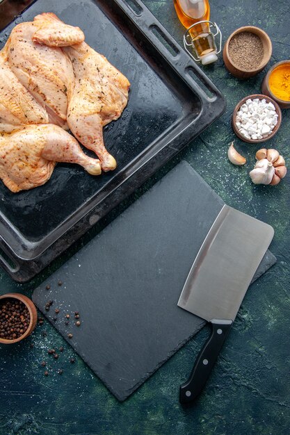 Top view fresh spiced chicken with seasonings on dark-blue background food spice pepper dish dinner meat color baking