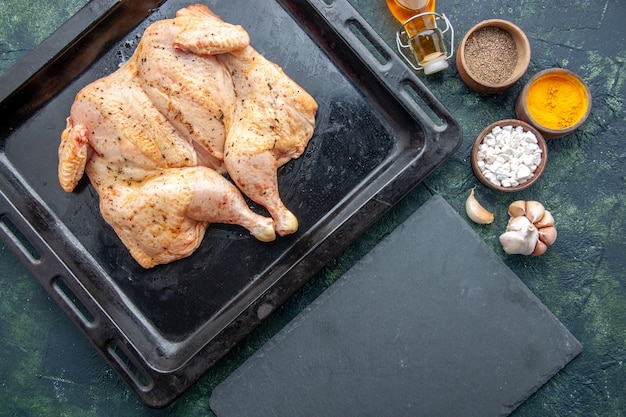 Top view fresh spiced chicken with seasonings on the dark-blue background food spice pepper dish dinner meat color salt baking