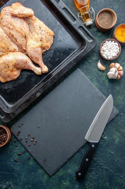 Top view fresh spiced chicken with seasonings on dark-blue background food spice pepper dish dinner meat color salt