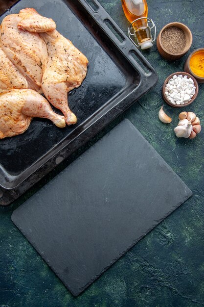 Top view fresh spiced chicken with seasonings on dark-blue background food spice pepper dish meat color salt baking