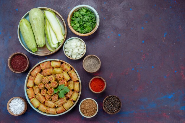 Top view fresh squashes with greens and seasonings meat rolls on the dark-purple desk meat dinner vegetable meal