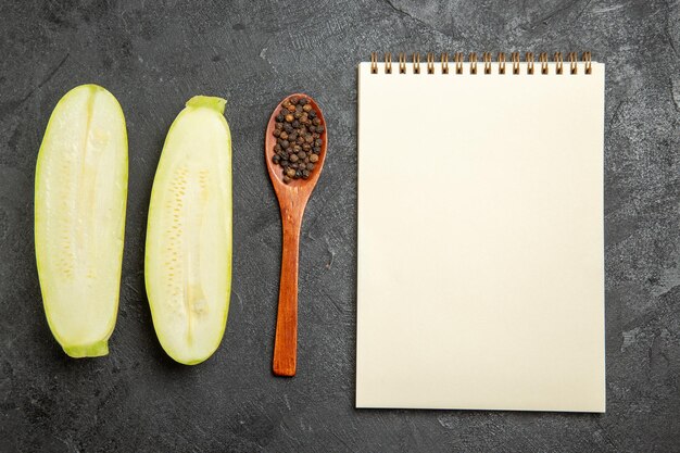 Top view of fresh squashes with notepad on grey surface