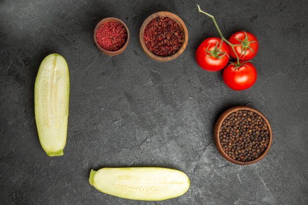 Top view of fresh squashes with seasonings and tomatoes on grey surface