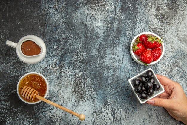 Free photo top view fresh strawberries with olives and honey on dark surface berry sweet fruit