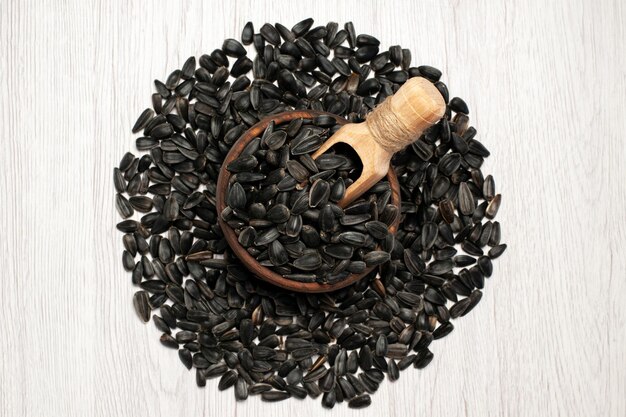 Top view fresh sunflower seeds black colored seeds on a white desk photo oil snack many seed