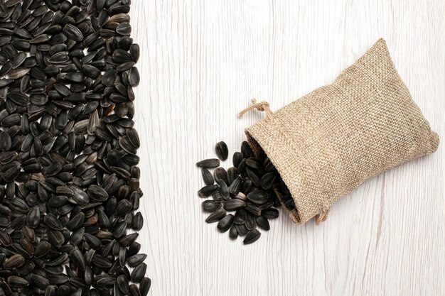 Top view fresh sunflower seeds black colored seeds on white surface seed corns snack photo many oil