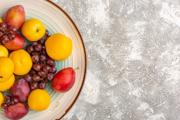 Free photo top view fresh sweet apricots with red grapes and plums inside plate on the white surface