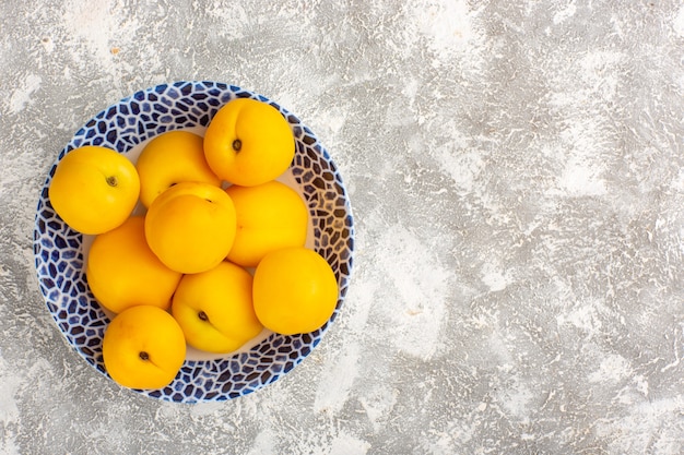 Top view fresh sweet apricots yellow fruits inside plate on the white surface