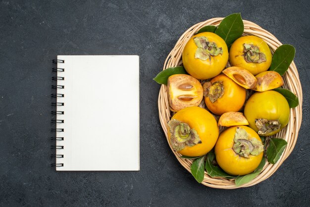 Top view fresh sweet persimmons inside basket on dark table fruit ripe
