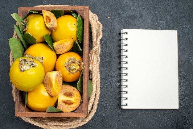 Top view fresh sweet persimmons inside box on dark floor taste ripe fruit