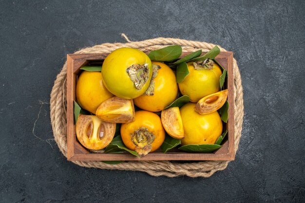 Top view fresh sweet persimmons inside box on dark table taste ripe fruits