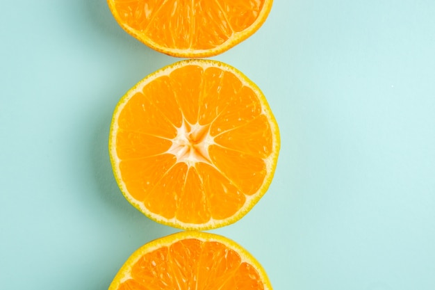 Top view fresh tangerine slices lined on the light-blue background