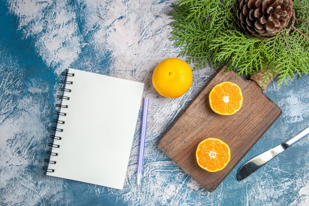 Top view fresh tangerine slices with notepad on light-blue background