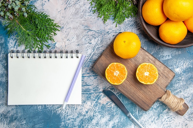 Top view fresh tangerine slices with notepad on light-blue background