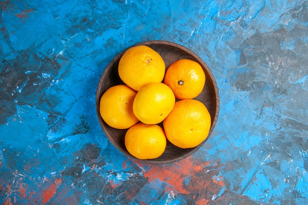 Top view fresh tangerines inside plate on the blue background