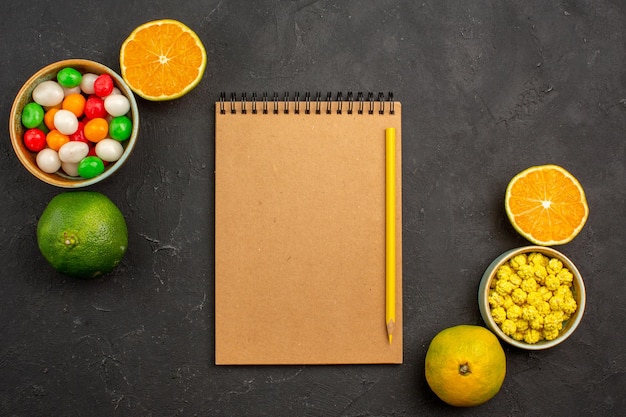 Top view of fresh tangerines with candies on black table