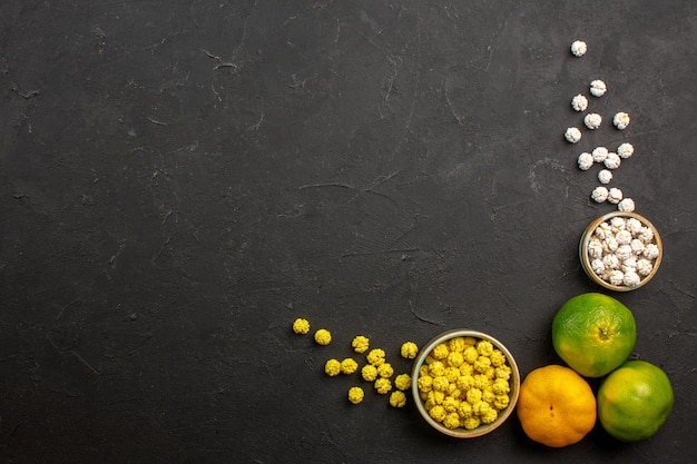 Top view of fresh tangerines with candies on grey table