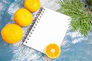 Free photo top view fresh tangerines with notepad on light-blue background