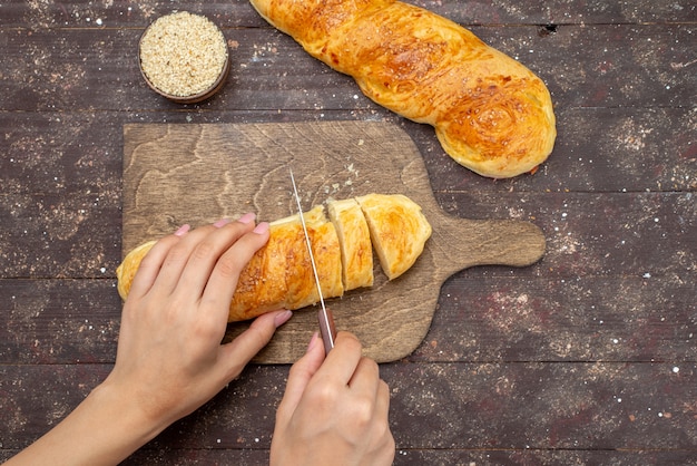 Top view fresh tasty pastry long bun formed getting cut pastry on the brown wooden desk bun pastry dough bread meal