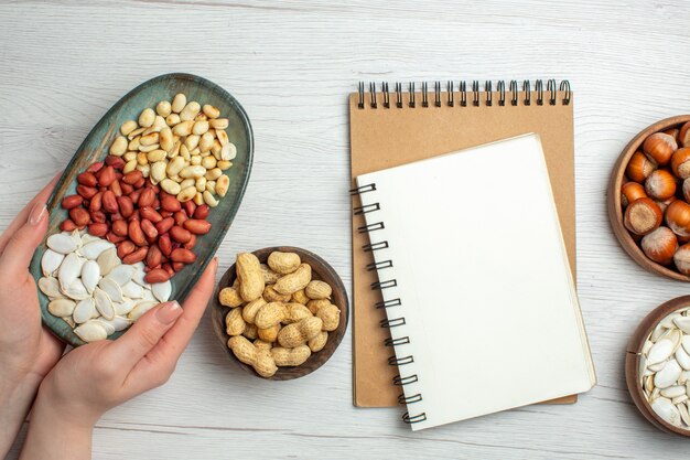 Top view fresh tasty peanuts with white seeds and hazelnuts on white table