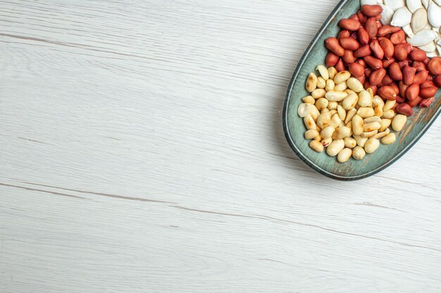 Top view fresh tasty peanuts with white seeds inside plate on white table