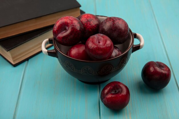 Top view of fresh tasty pluots on a bowl with pluots isolated on a blue wooden wall