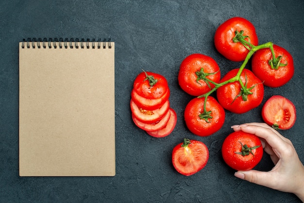 검은 탁자에 있는 여성용 수첩에 있는 신선한 토마토 가지 다진 토마토 빨간 토마토