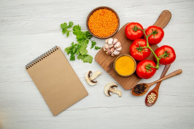 Top view fresh tomato branch garlic turmeric bowl on cutting board mushrooms lentile bowl parsley notebook on grey background