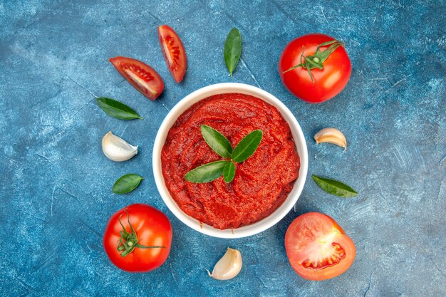 Top view fresh tomato paste with garlic and fresh tomatoes on blue table