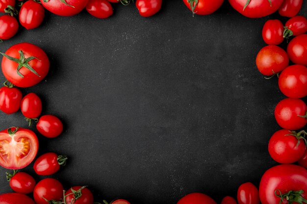 Top view of fresh tomatoes on black background with copy space