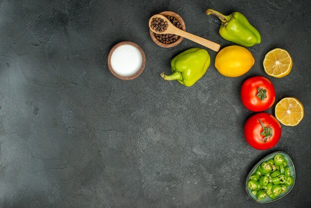 Top view fresh tomatoes with bell-peppers and lemon on dark background