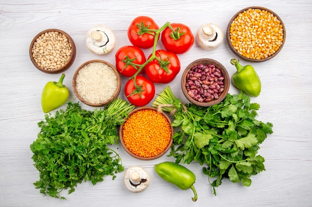 Free photo top view of fresh tomatoes with stem corn kernels beans bundle of greens mushrooms pepper on white background