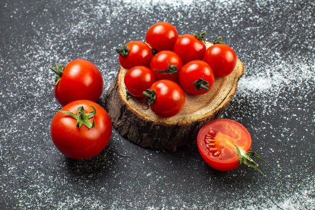 Top view of fresh tomatoes with stems on wooden board and on wite black background