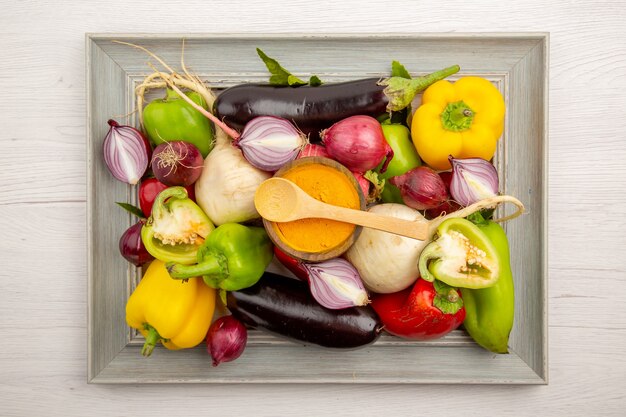 白いテーブルの上のフレーム内の新鮮な野菜の組成物の上面図